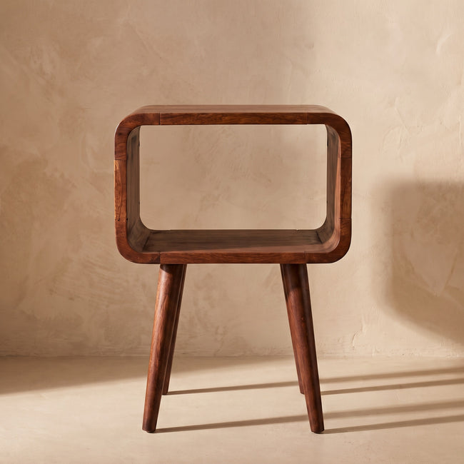 Chestnut bedside table with tapered legs standing beside a bed