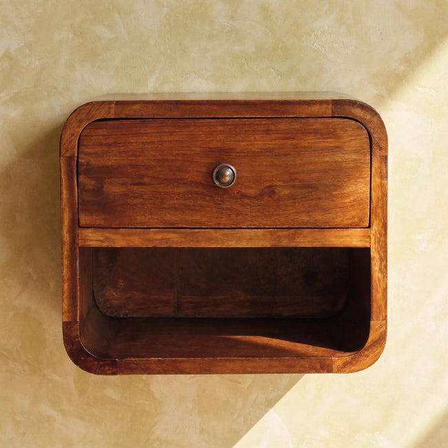 Wall-mounted mango wood bedside table with one drawer and one open slot beside a bed
