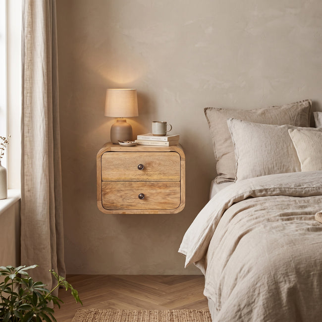 Mini Curve floating bedside table in an oak-ish finish mounted on a bedroom wall