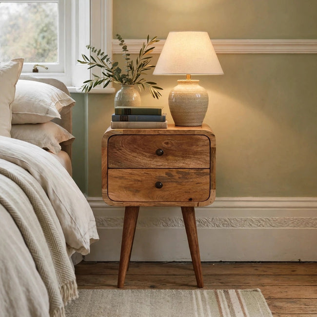 Mini curved mango wood bedside table with an oak-ish finish in a styled bedroom