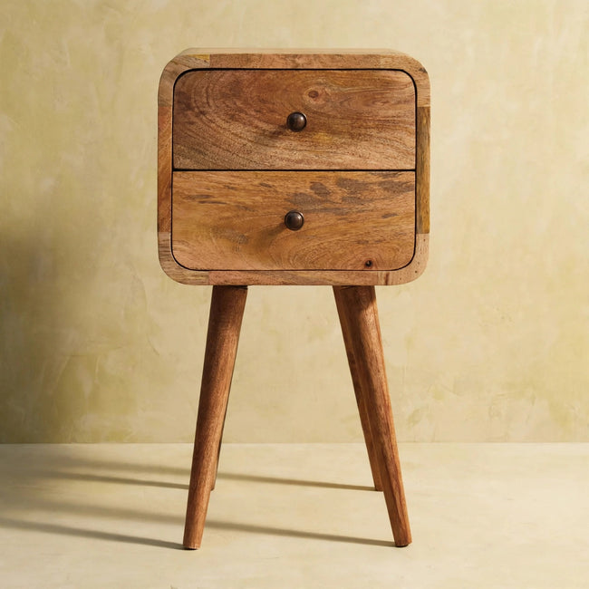 Small bedside table with two drawers and shiny knobs next to a bed