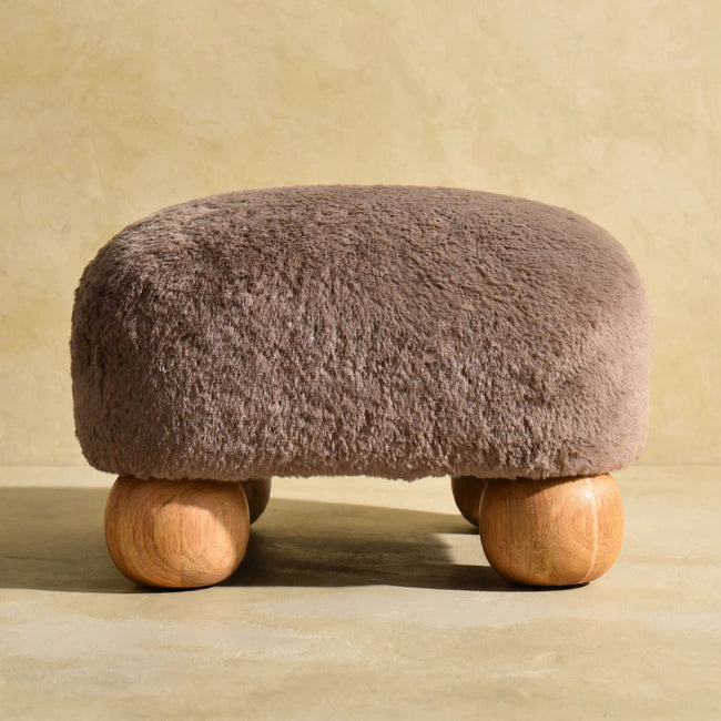 Square mocha faux fur footstool on solid mango wood bun feet, styled in a room