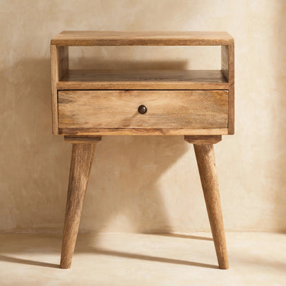 Oak-look solid mango wood bedside table with Nordic-style legs next to a bed