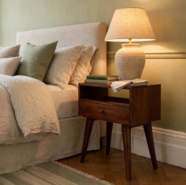 Chestnut solid mango wood bedside table with one drawer and a brass knob in a bedroom