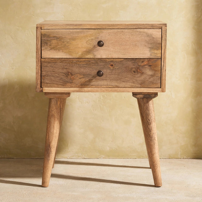 Oak-ish finish bedside table beside a bed with a lamp on top