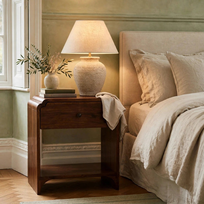 Newton bedside table in solid mango wood with a chestnut finish, shown in a bedroom setting