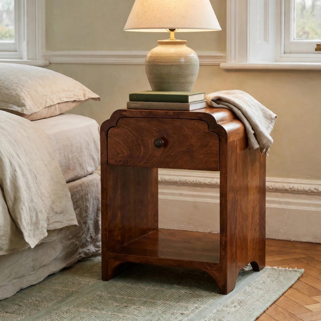 Newton Mini chestnut mango wood nightstand with a drawer and open shelf, shown in a bedroom setting