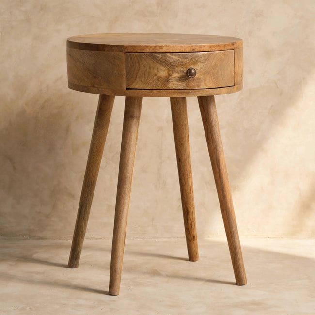 Nordic circular bedside table standing beside a bed in a styled room