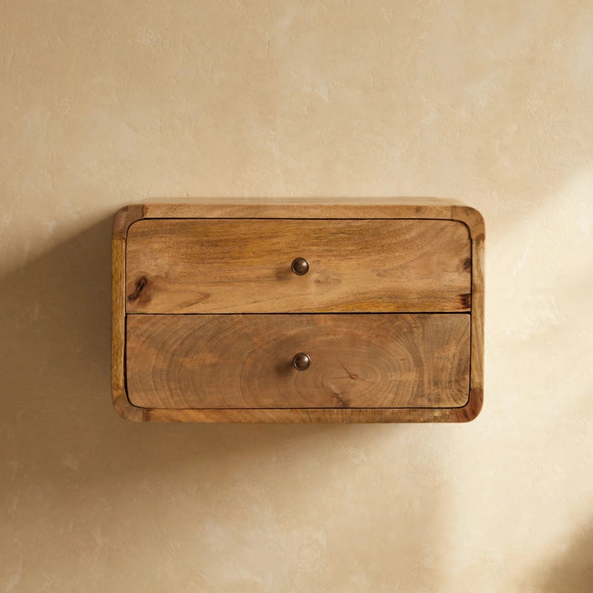 Wall-mounted solid mango wood bedside table with two drawers beside a bed