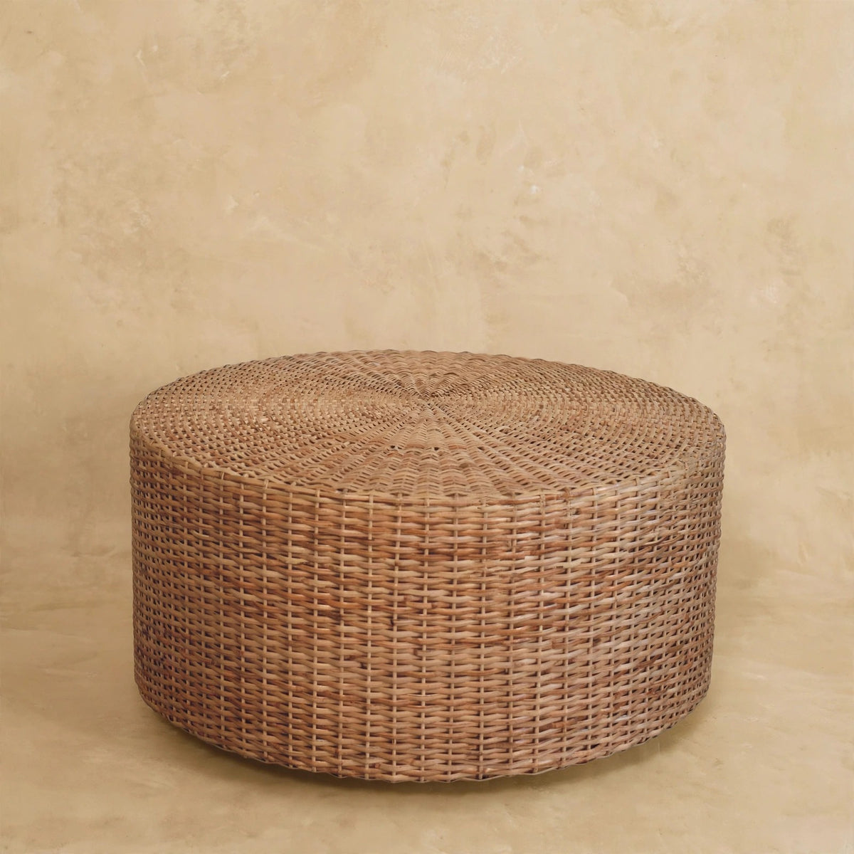 Round woven coffee table placed in front of a sofa in a living room