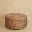 Round woven coffee table placed in front of a sofa in a living room