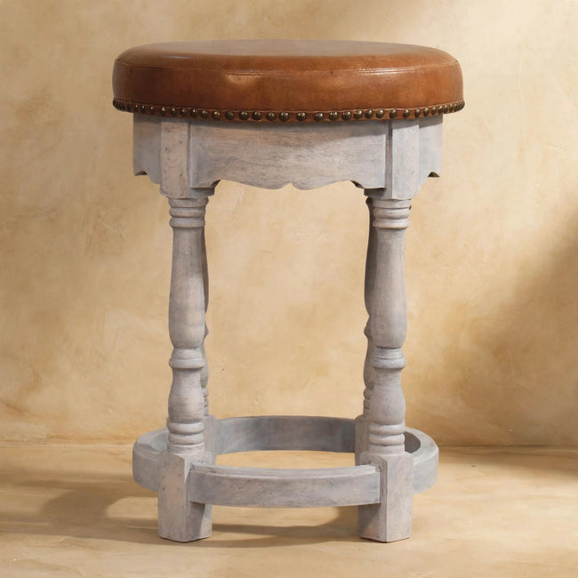 Brown leather seat with antique brass studs on the mango wood frame of the Rustic Charm stool