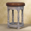 Side view of the Rustic Charm stool showing turned mango wood legs and scalloped apron