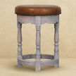 Close-up of the acid wash mango wood finish and leather seat of the Rustic Charm stool