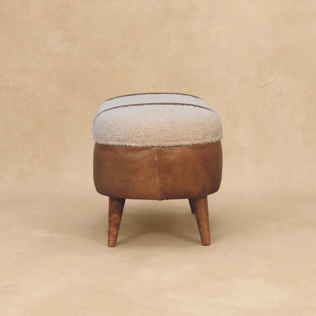 Angled view of the tan boucle and buffalo leather bench in a room