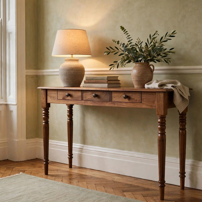 Three drawer console table in Honey Caramel mango wood with turned legs, shown in a room setting