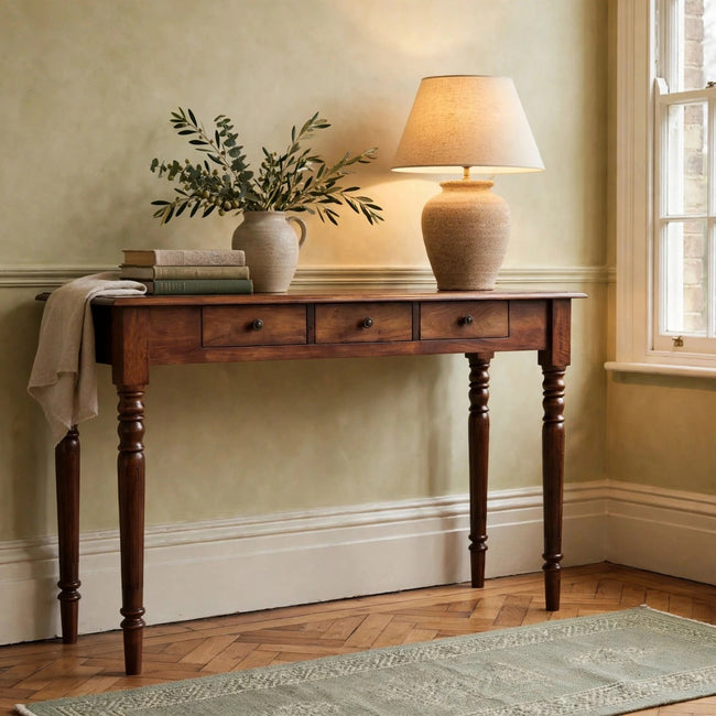 Chestnut mango wood console table with three drawers and turned legs in a styled hallway