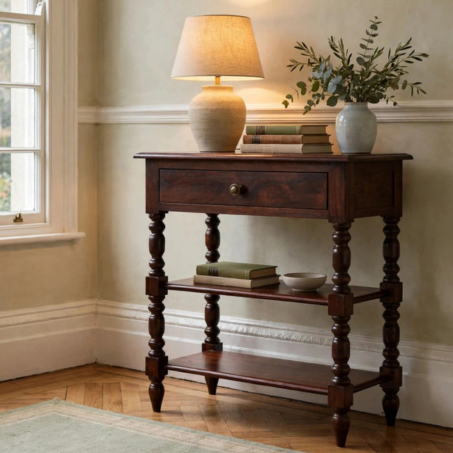 Turned occasional table in solid mango wood with a drawer and two shelves, shown in a living room