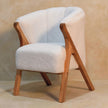 White boucle chair placed in a bright living space beside simple decor
