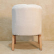 White boucle accent chair in a room, showing the full chair with wooden legs