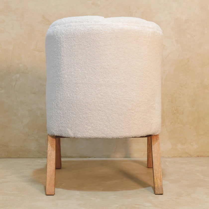 White boucle accent chair in a room, showing the full chair with wooden legs